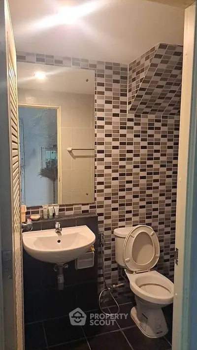 Compact bathroom with modern tile design and essential fixtures