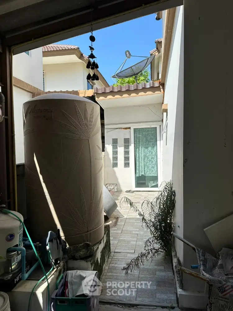 Charming outdoor utility area with water tank and satellite dish in a cozy residential setting.