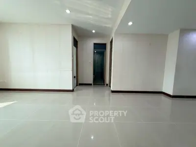 Spacious empty room with tiled flooring and recessed lighting, ideal for customization.