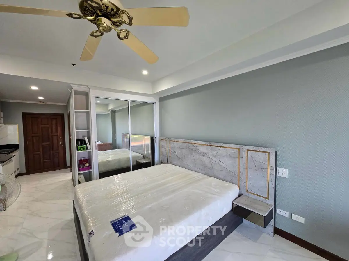 Spacious bedroom with modern design and mirrored wardrobe in a luxury apartment.