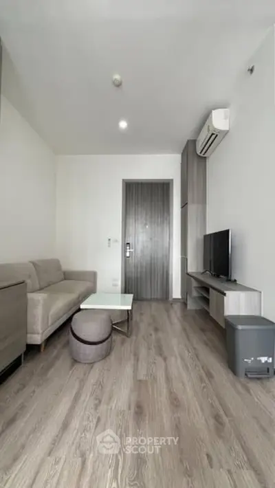Modern living room with sleek furniture and wooden flooring, featuring a cozy sofa and flat-screen TV.