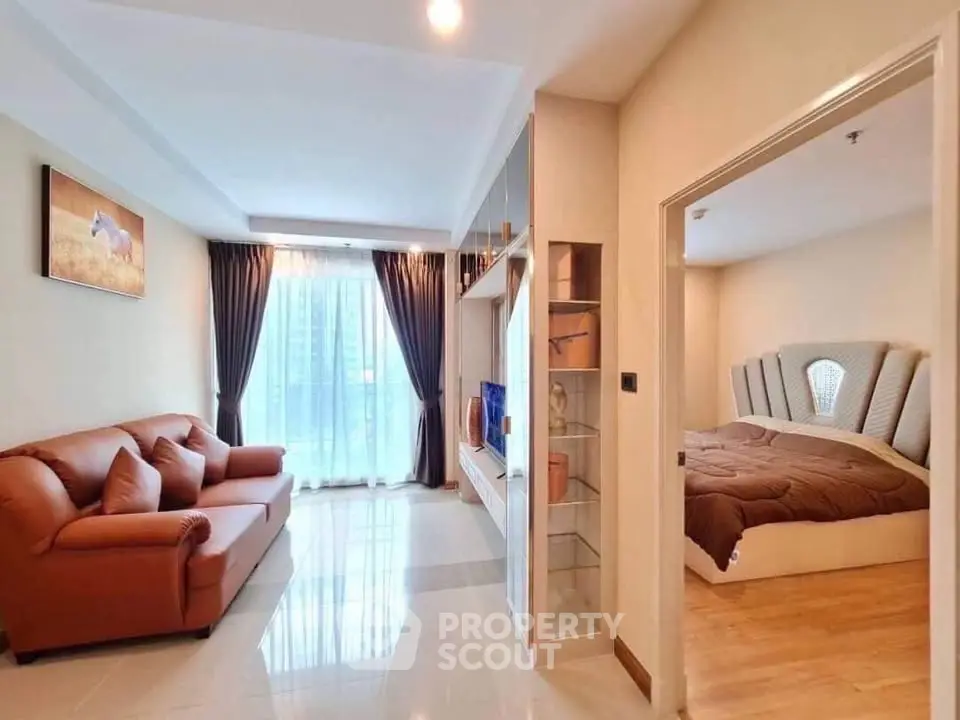 Spacious living room with elegant decor and adjacent cozy bedroom in modern apartment.