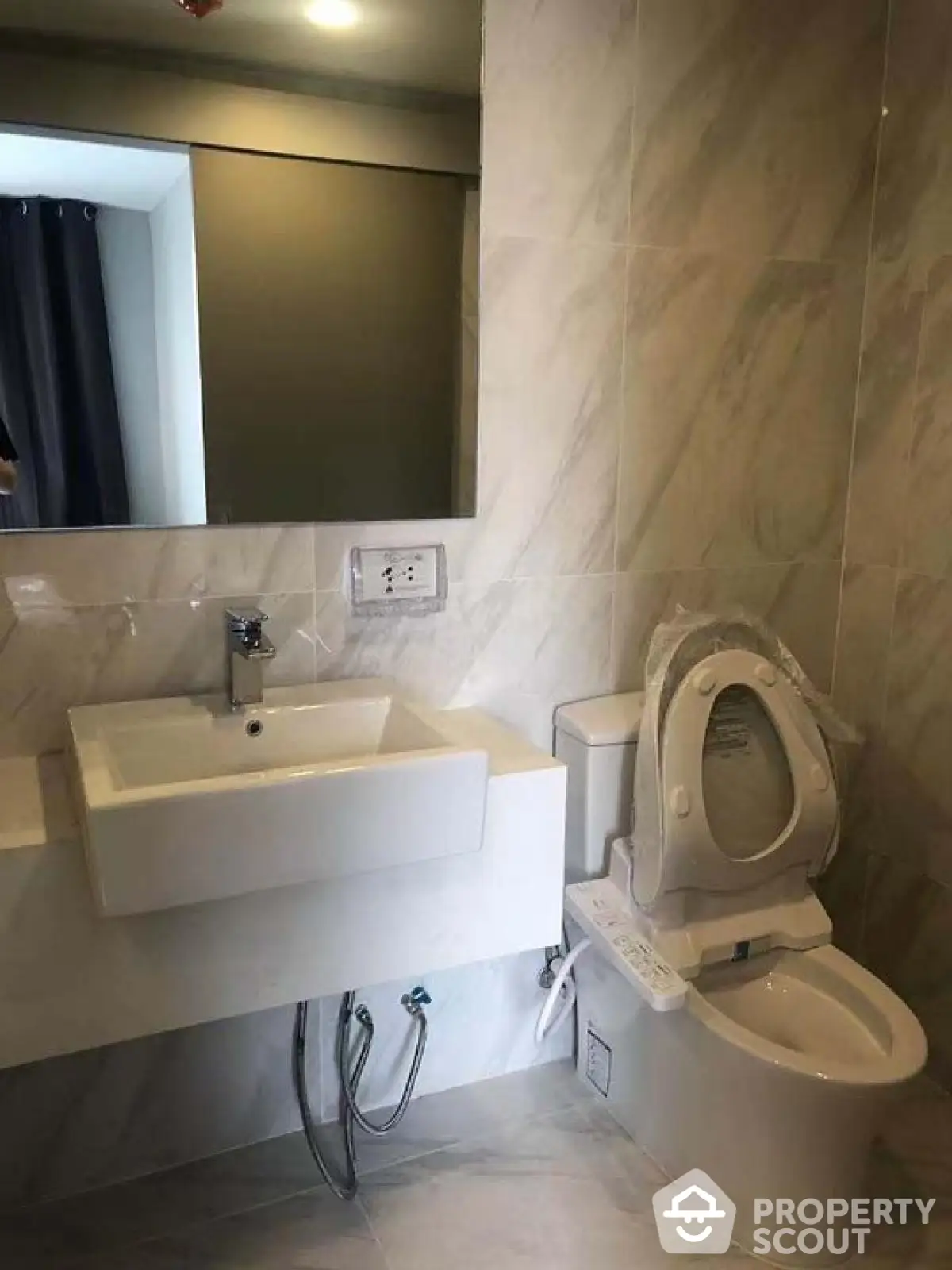 Modern bathroom with sleek sink and toilet in marble setting