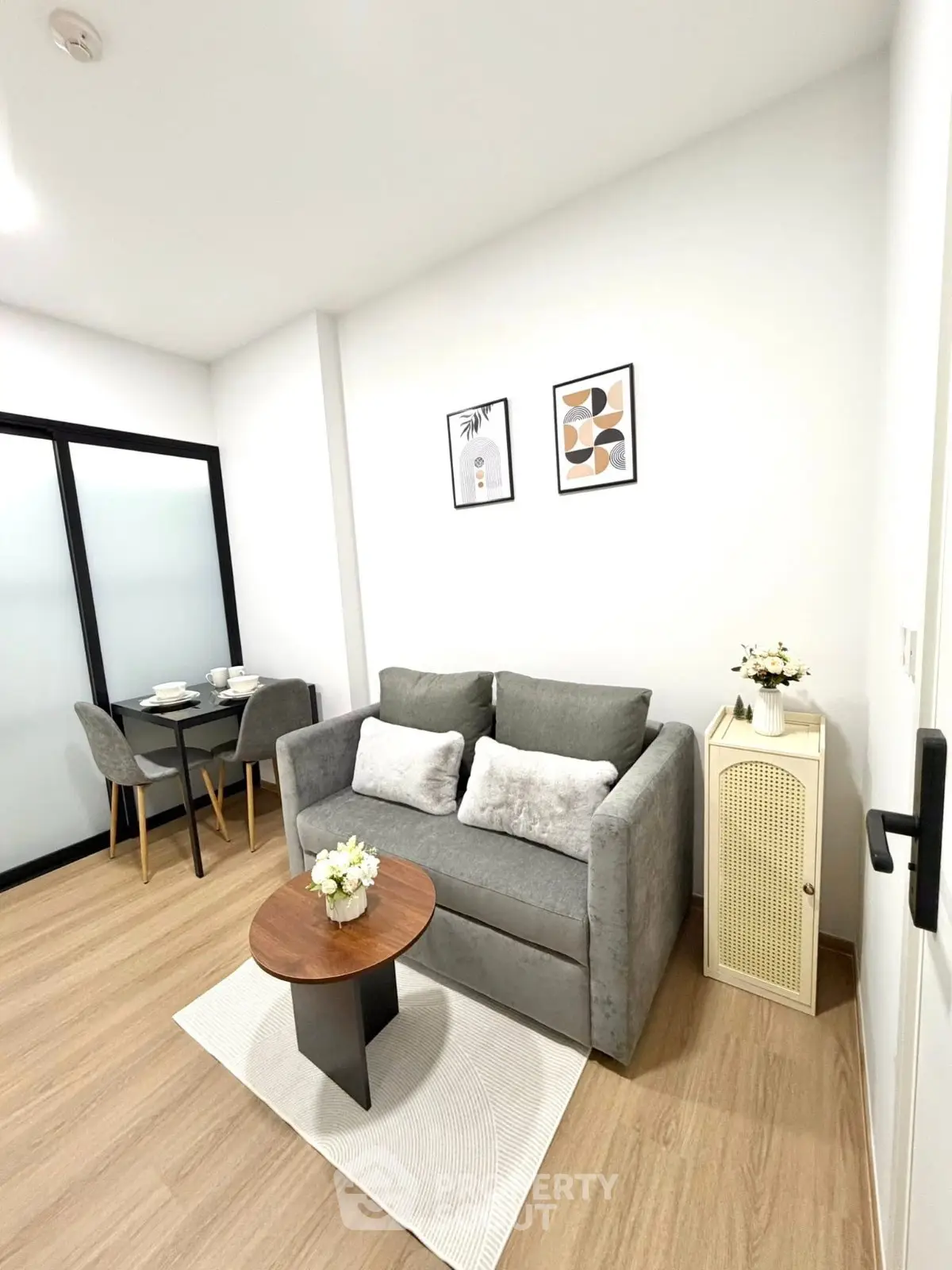 Modern living room with cozy gray sofa, stylish decor, and dining area in a chic apartment.