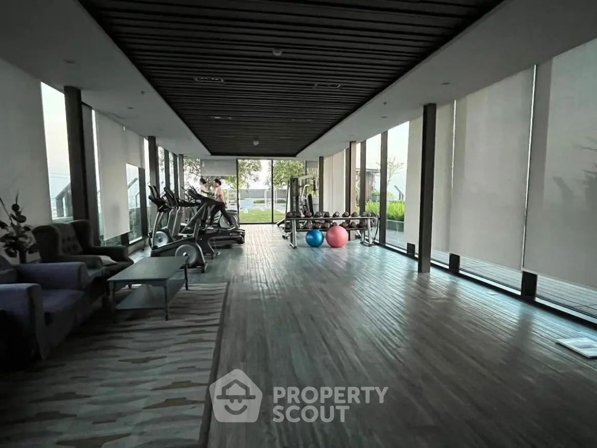 Spacious modern gym with large windows and exercise equipment in luxury real estate property.