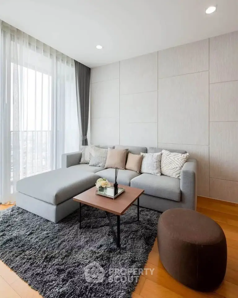 Modern living room with stylish gray sofa, cozy rug, and elegant decor in a bright apartment.