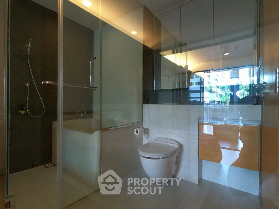 Luxurious modern bathroom with glass shower and sleek fixtures in upscale apartment.