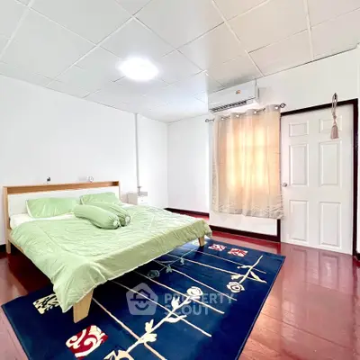 Spacious bedroom with modern decor and vibrant rug in a cozy home.