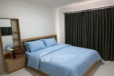 Cozy bedroom with modern wooden furniture and soft blue bedding, perfect for relaxation.