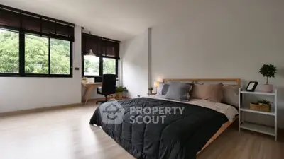 Spacious bedroom with large windows offering a serene view, modern furnishings, and ample natural light, perfect for relaxation.