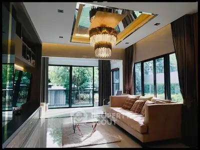 Luxurious living room with elegant chandelier and large windows overlooking greenery.