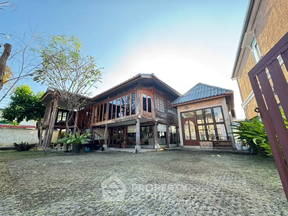 Charming traditional wooden house with spacious courtyard and lush greenery, perfect for serene living.