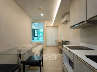 Modern open-layout living room with kitchen, featuring sleek design and natural light.