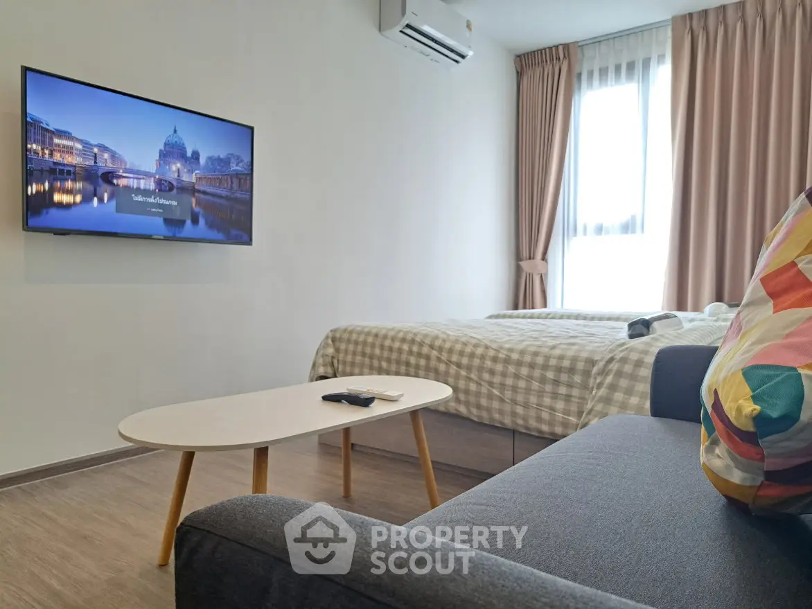 Modern studio apartment with cozy living area and wall-mounted TV, featuring a comfortable bed and stylish decor.