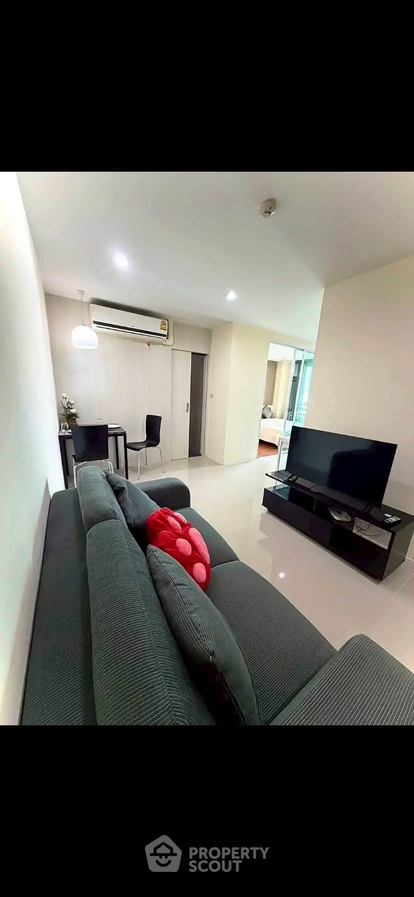 Modern living room with sleek furniture and open layout, featuring a cozy sofa and flat-screen TV.
