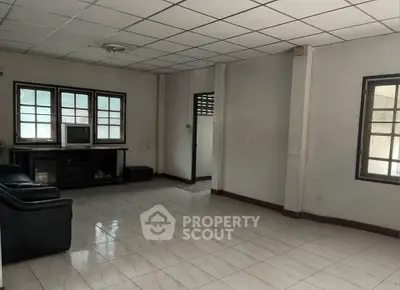 Spacious living room with tiled floor and ample natural light from multiple windows.
