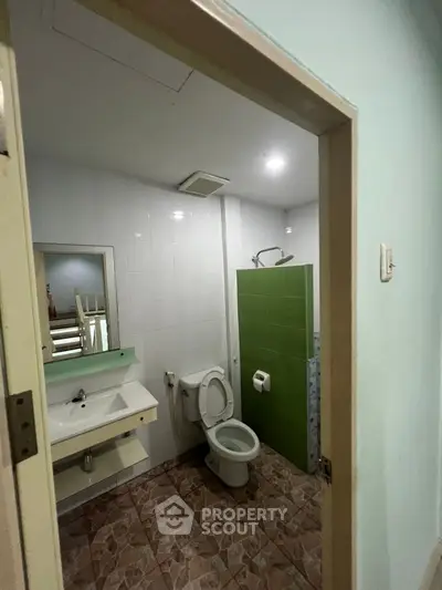 Compact bathroom with modern fixtures and tiled flooring, featuring a shower and toilet.