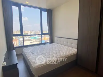 Modern bedroom with large window offering city view and stylish furnishings.