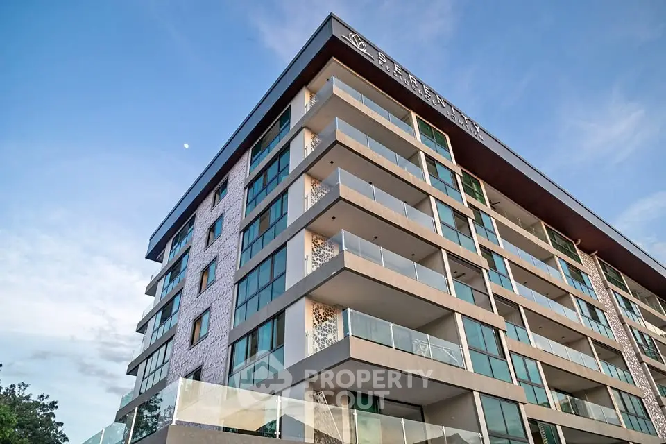 Modern multi-story residential building with spacious balconies and glass facade.