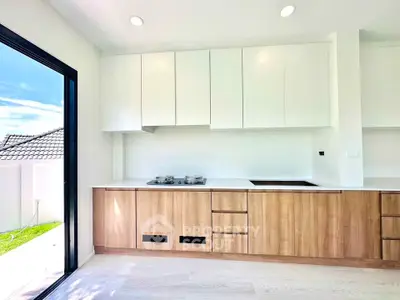 Modern kitchen with sleek cabinetry and gas stove, bright natural light from large window.