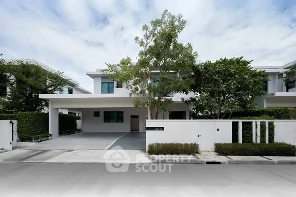 Modern two-story house with spacious driveway and lush greenery