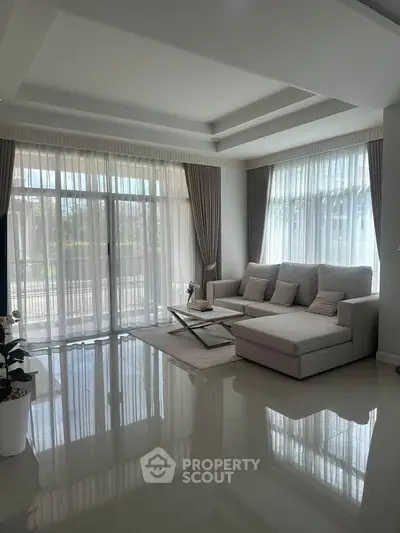 Elegant living room with large windows and modern furniture, offering a bright and inviting atmosphere.