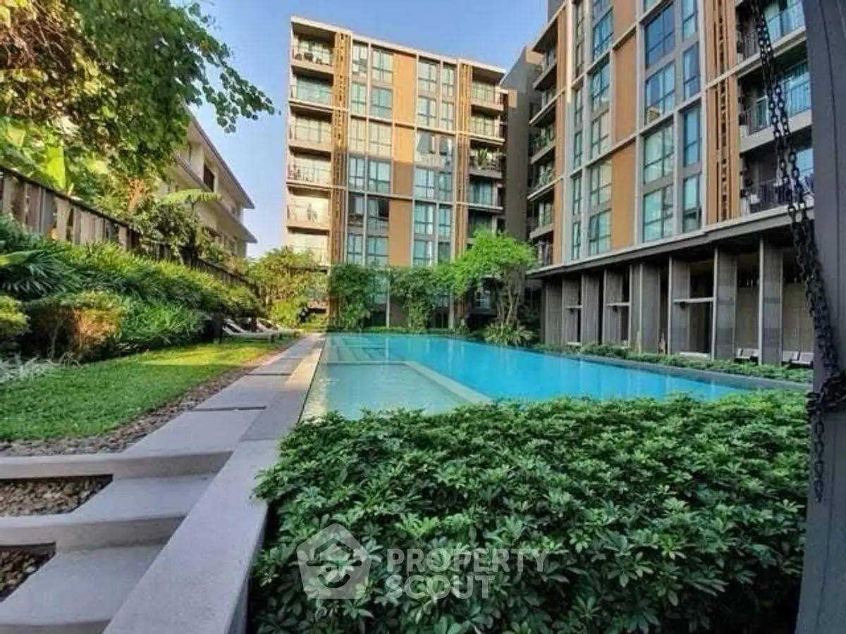 Modern apartment complex with lush garden and inviting swimming pool