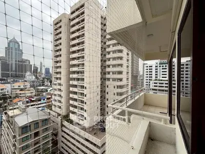 High-rise balcony with cityscape view and safety netting in urban setting.