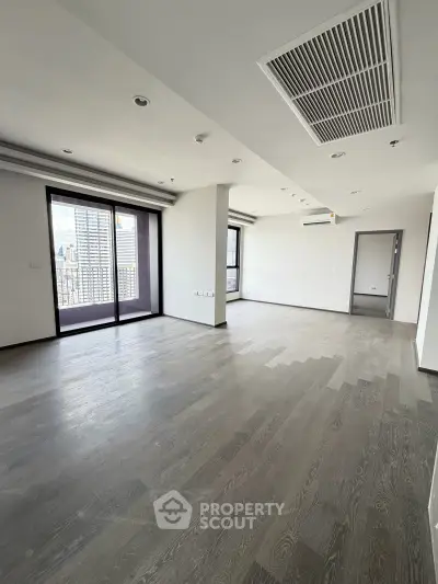 Spacious modern living room with large windows and city view, perfect for urban living.