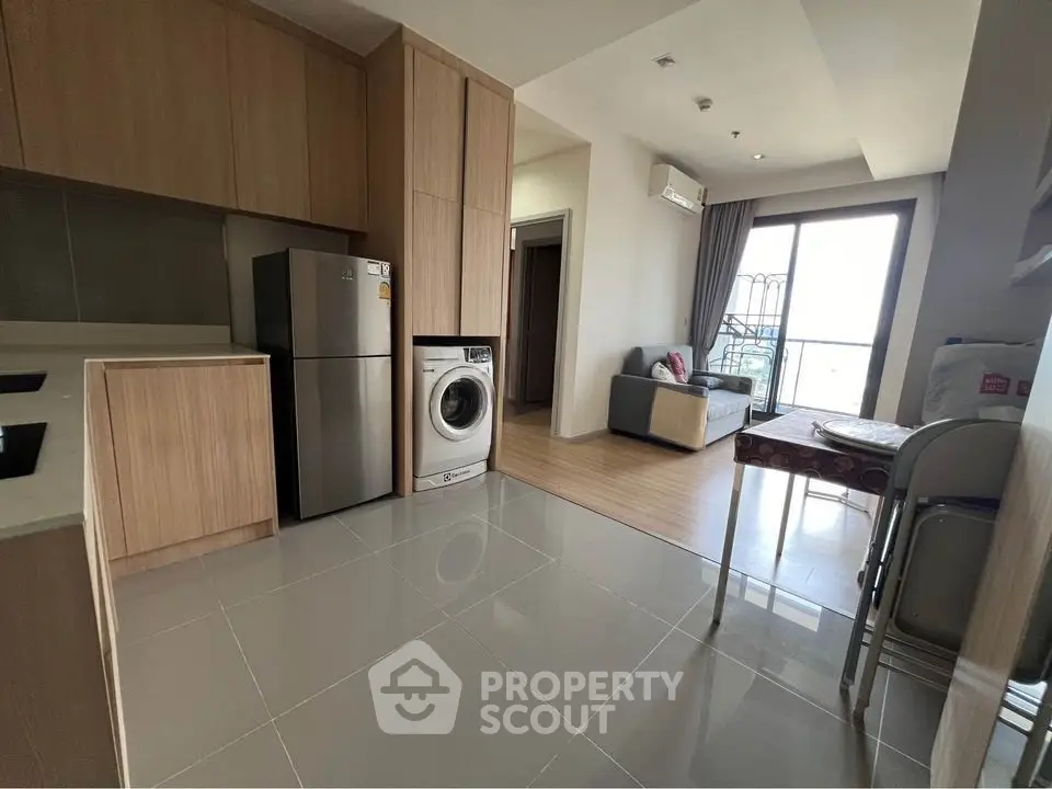 Modern apartment with open kitchen, washing machine, and cozy living area with balcony access.