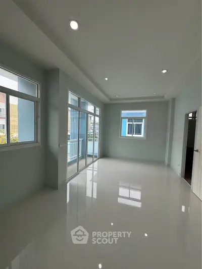 Spacious modern living room with large windows and glossy floors