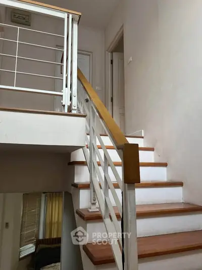 Charming interior staircase with wooden steps and white railing in a cozy home setting.