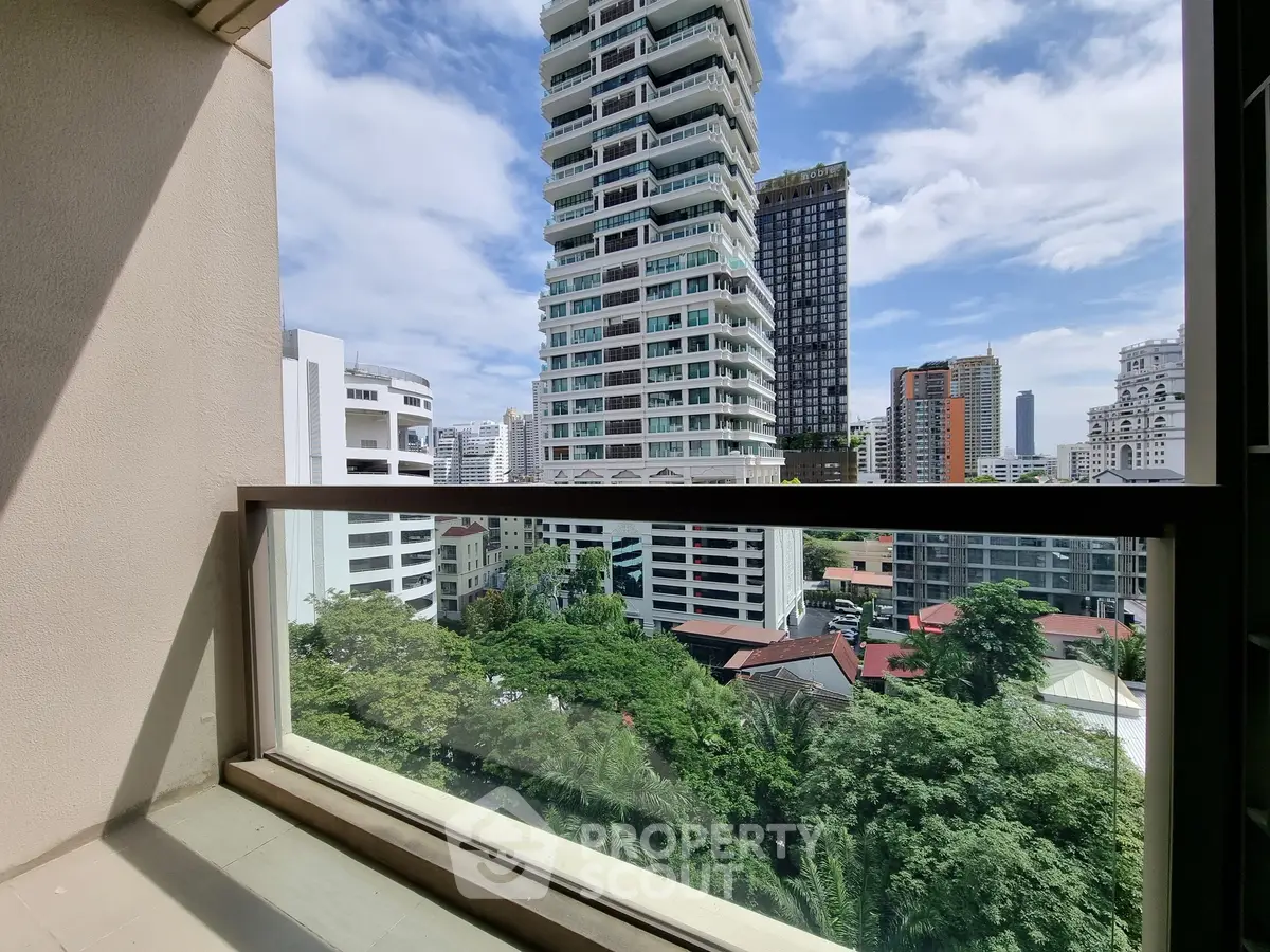 Stunning cityscape view from a modern balcony with lush greenery and skyscrapers.