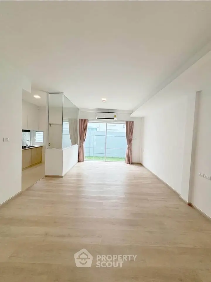 Spacious modern living room with large windows and light wood flooring