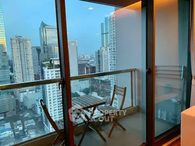 Stunning cityscape view from a modern high-rise balcony with cozy seating.