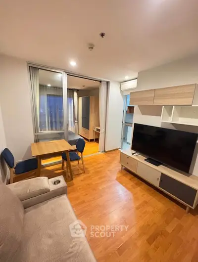 Modern living room with wooden flooring, cozy sofa, dining table, and large TV unit in a stylish apartment.