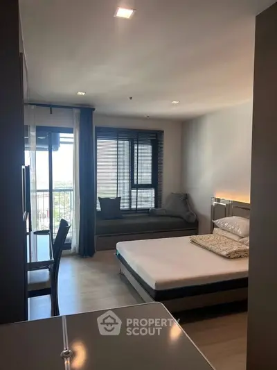 Modern bedroom with large window and cozy seating area, perfect for relaxation and natural light.