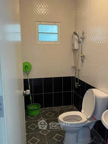 Modern bathroom with tiled walls and floor, featuring a toilet and shower area.