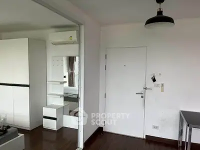 Modern apartment interior with sleek white furniture and dark wood flooring, featuring a cozy bedroom and stylish lighting.