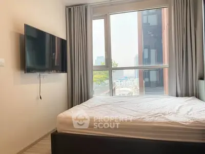 Modern bedroom with large window and wall-mounted TV in urban apartment