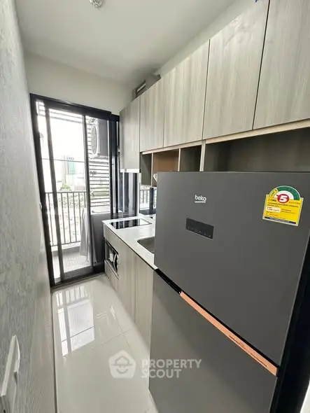 Modern compact kitchen with sleek appliances and balcony access