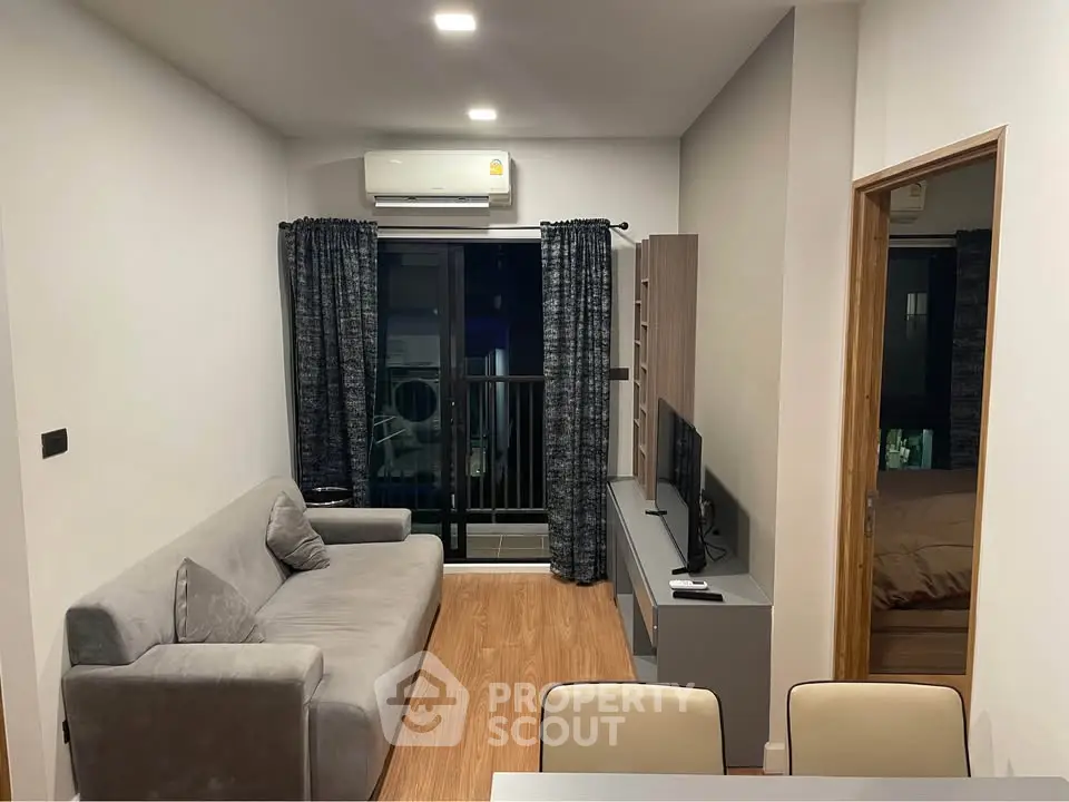 Modern living room with cozy sofa, sleek TV unit, and balcony access in stylish apartment.