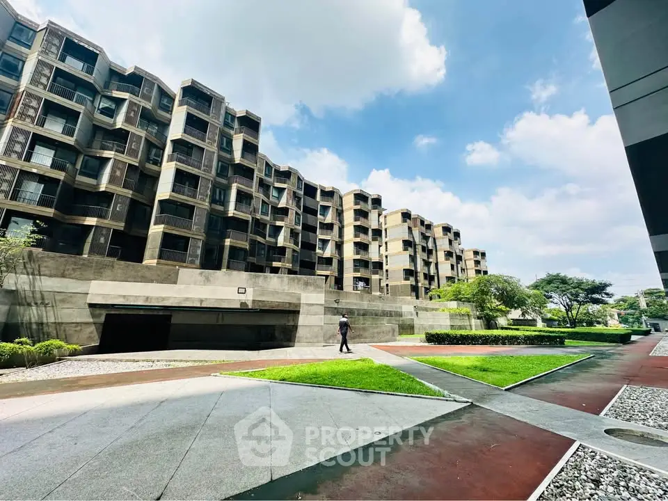 Modern architectural building with lush green surroundings and clear blue sky.