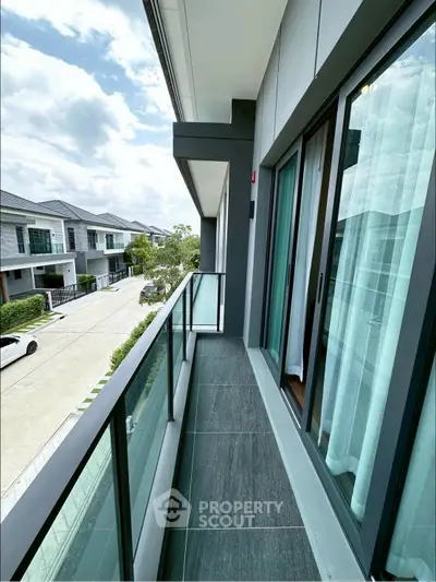 Modern balcony with glass railing and street view in upscale neighborhood