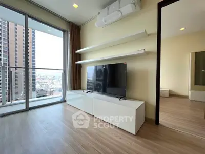 Modern living room with sleek TV unit and balcony view in high-rise apartment