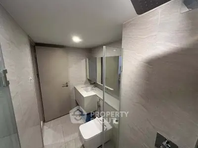 Modern bathroom with sleek design, featuring a glass shower and contemporary fixtures.