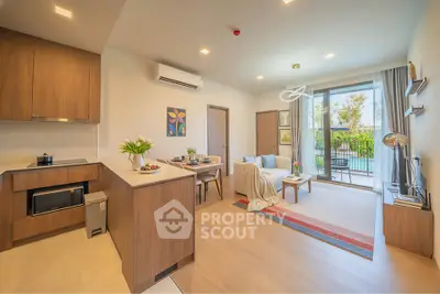 Modern open-plan living room with kitchen, featuring stylish decor and access to a lush balcony.