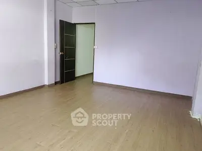 Spacious empty room with wooden flooring and a modern door, ideal for customization.