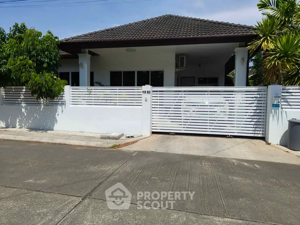Charming single-story home with modern fence and lush greenery in a serene neighborhood.