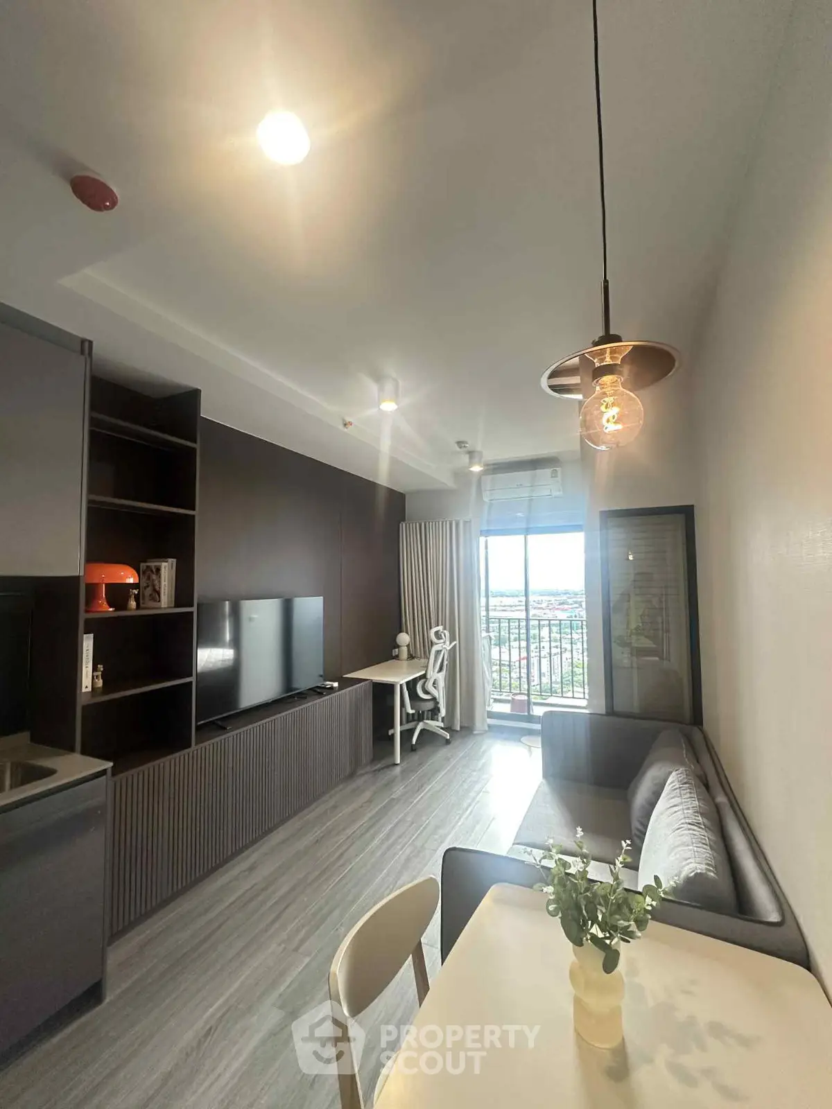 Modern living room with stylish decor and balcony view in a high-rise apartment.